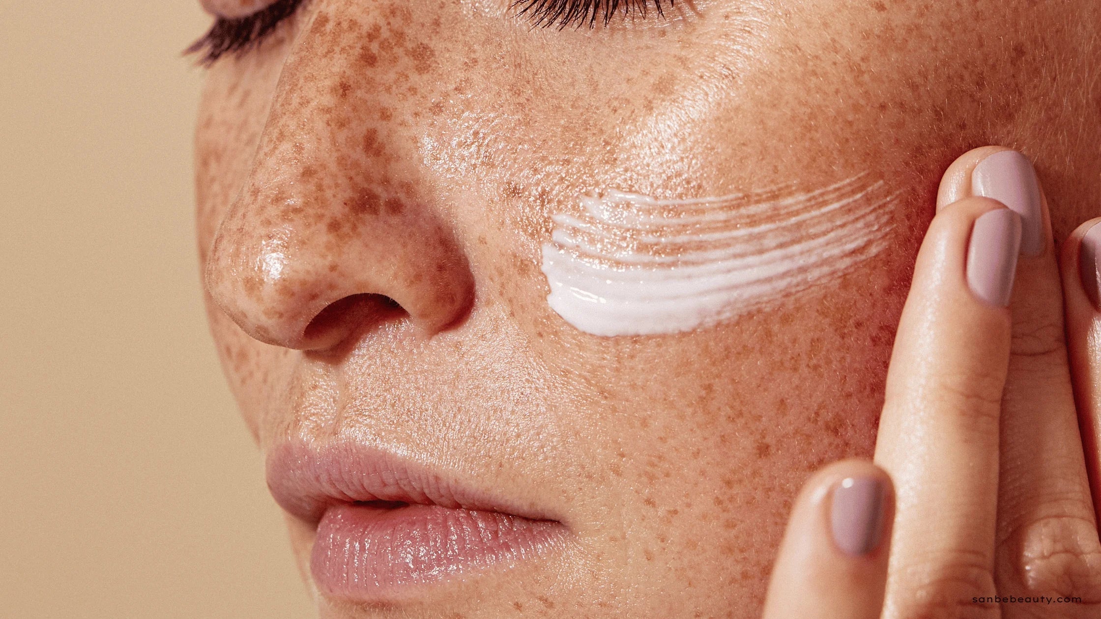 Close-up of human skin with freckles, cream applied